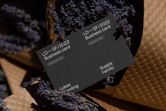 Elegant black business card mockup with white typography, set against a backdrop of dried lavender and textured paper, ideal for designers.