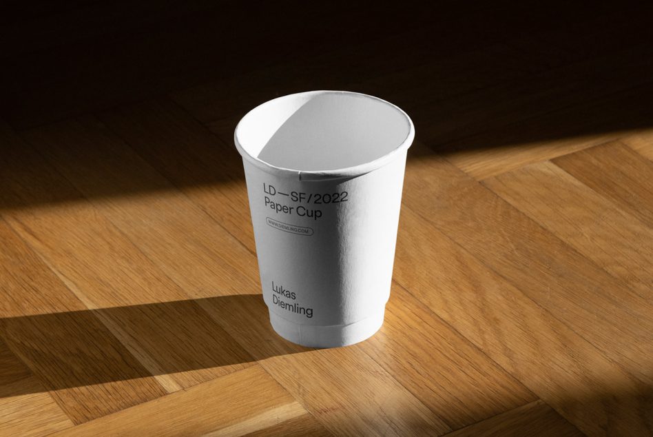 Photorealistic paper cup mockup on wooden surface with natural shadows, suitable for branding and packaging design presentations.