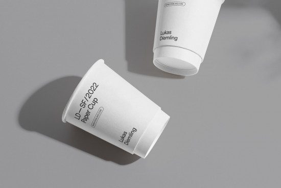 Paper cup mockup with modern design, customizable branding for designers, presented in shadowed minimalist setting for graphic display.