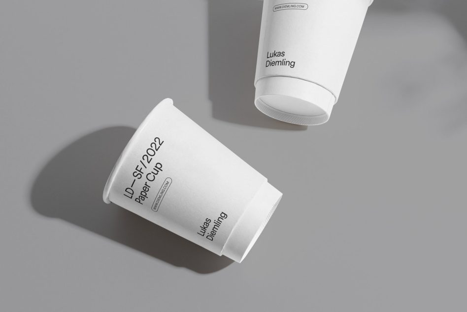 Two white paper cups stacked with minimal typography on neutral gray