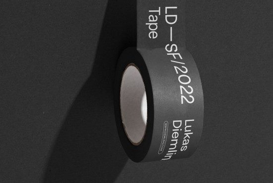 Black adhesive tape roll with white typographic design on dark background, ideal for mockup material, graphic design, and creative presentation.