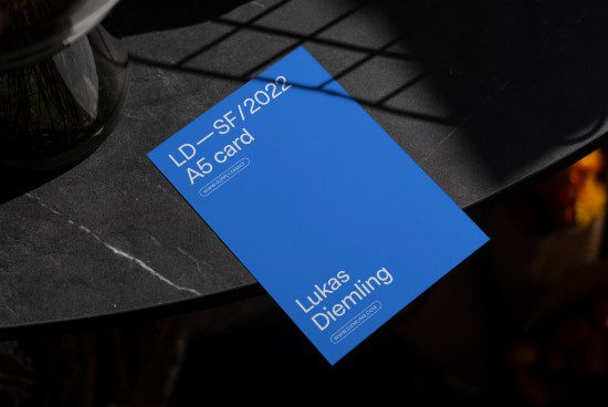 Creative A5 card mockup on a dark textured surface with natural light shadow, ideal for presenting fonts and graphic designs.