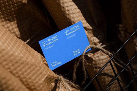 Blue business card mockup with modern design in a wire basket on a kraft paper background, perfect for graphic designers.