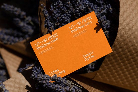 Orange business card mockup with elegant typography, placed on natural lavender flowers, showcasing design for branding in a rustic setting.