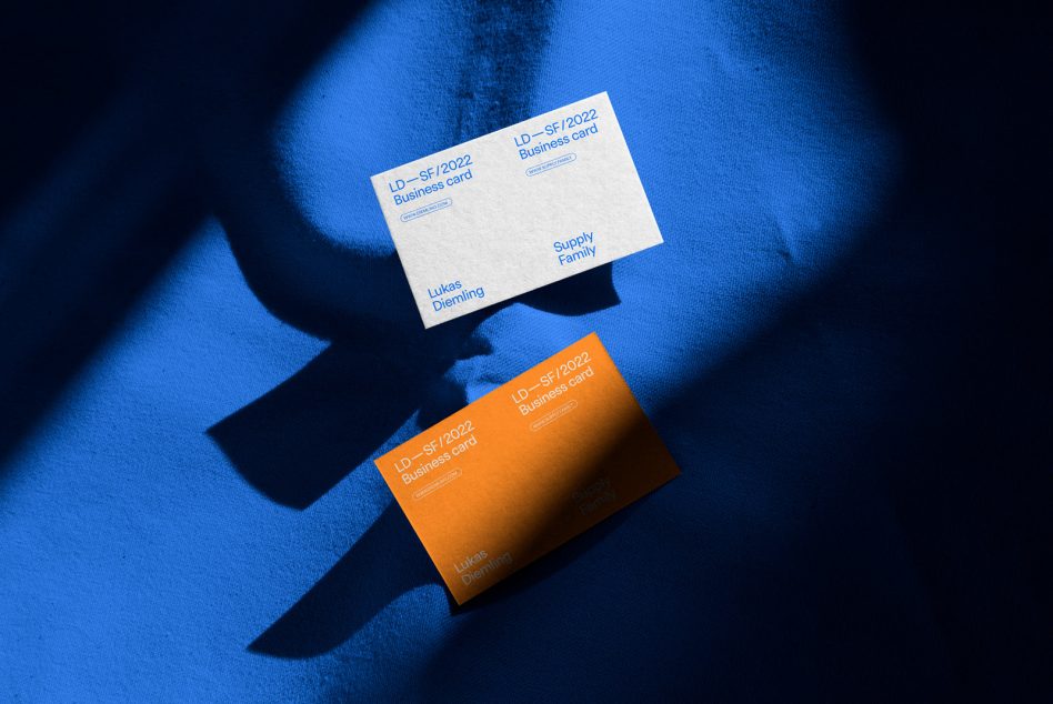 White, orange, blue business cards on fabric with dramatic shadows cast