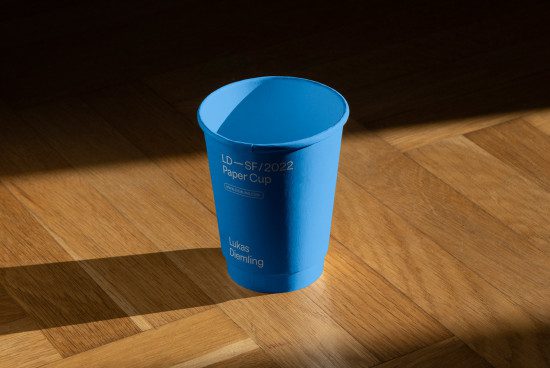 Blue paper cup mockup on a wooden surface with shadow, realistic branding presentation, packaging design, designer asset.