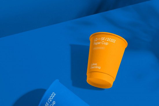 Orange paper cup mockup on blue background, ideal for presenting logo designs or branding work, perfect graphic template for designers.