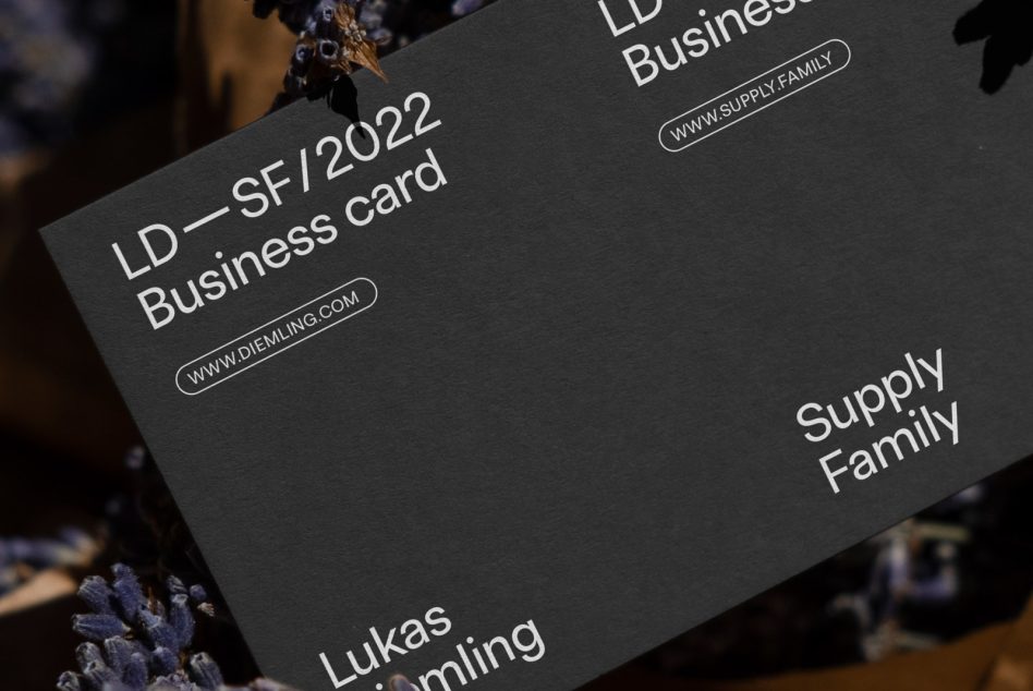 Dark business card angled on moody background with dried flower accent