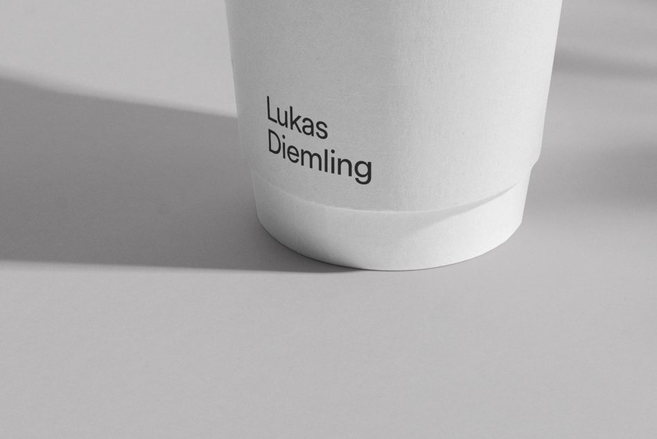 Paper cup mockup with a name shadow on a plain background, showcasing branding potential for designers and display of fonts.