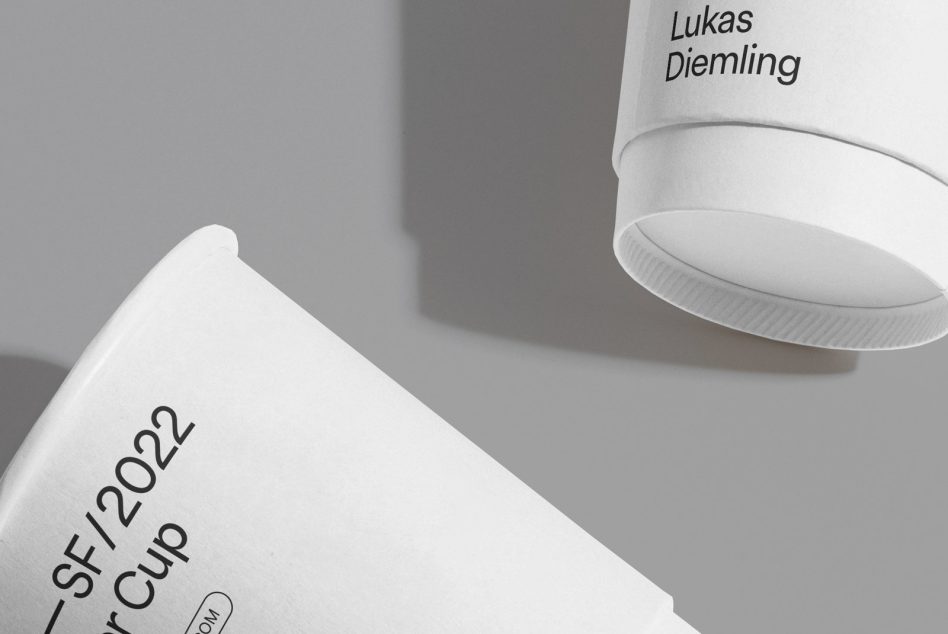 White takeout cup angled showing black text label on clean gray surface