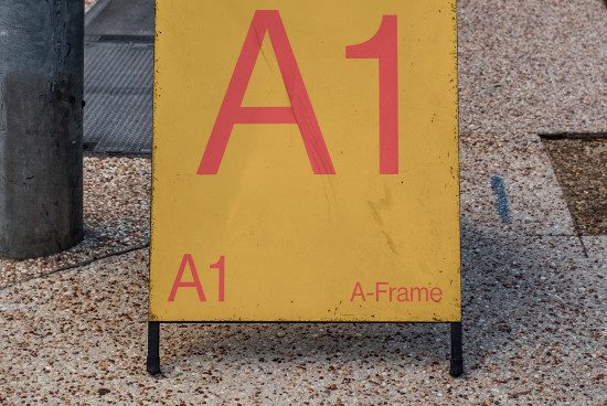 Yellow A-Frame sign with bold red A1 text, worn textured surface, urban outdoor setting, ideal for mockup designs and templates.