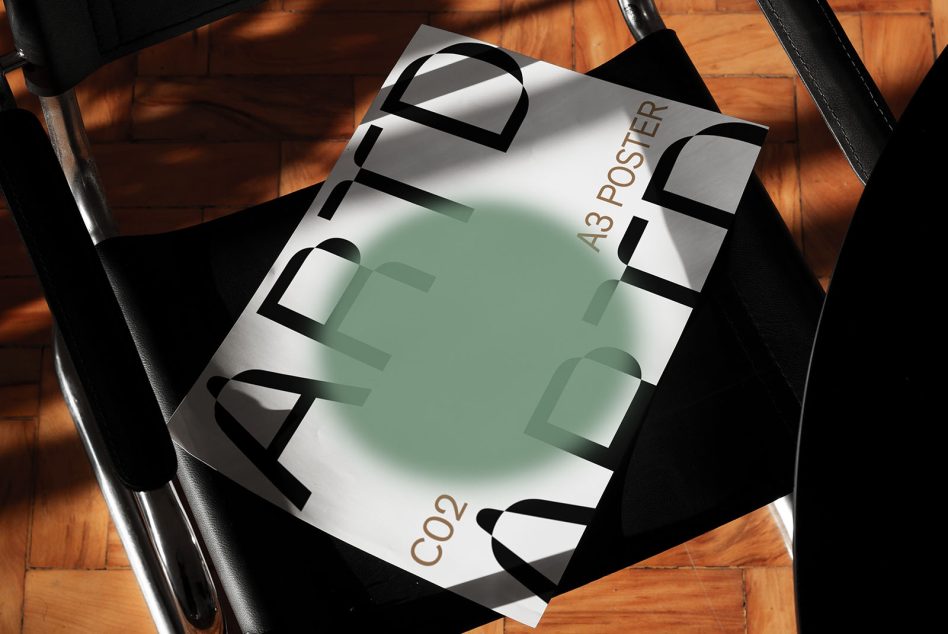 Sage green tinted poster held in black hands above wooden flooring with strong shadows