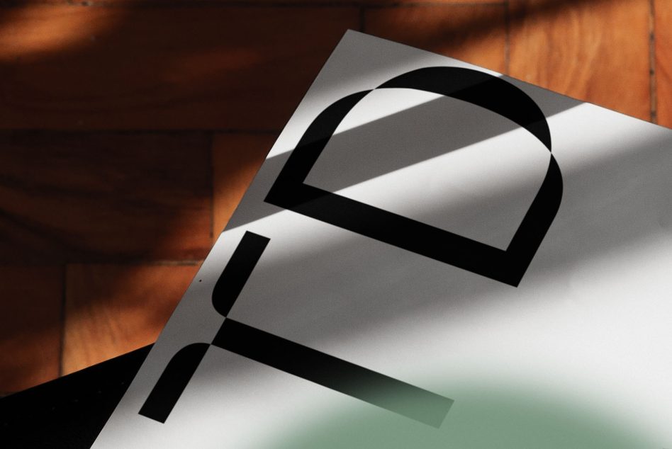 White paper mockup with black abstract forms, angled on warm wood surface