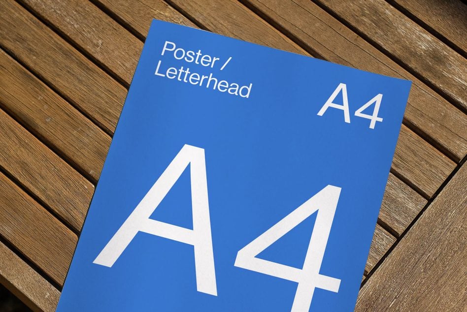 Bright blue A4 poster mockup with bold white letters on wooden surface