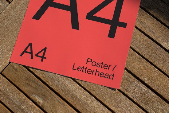 A4 sized red poster mockup on a wooden surface, ideal for displaying design work for branding, letterheads, and graphics templates.