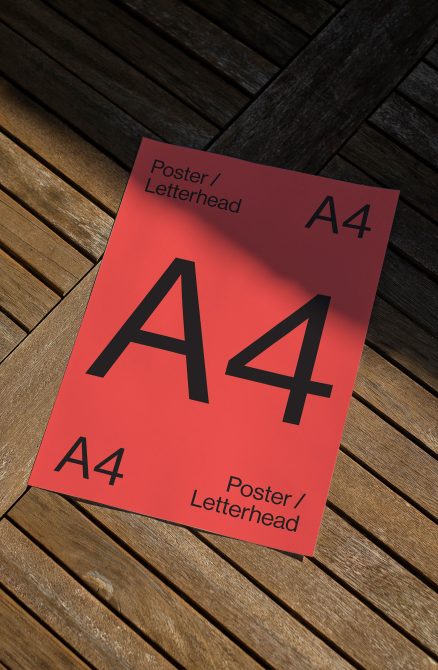 Red A4 poster mockup with black letters on herringbone wood surface