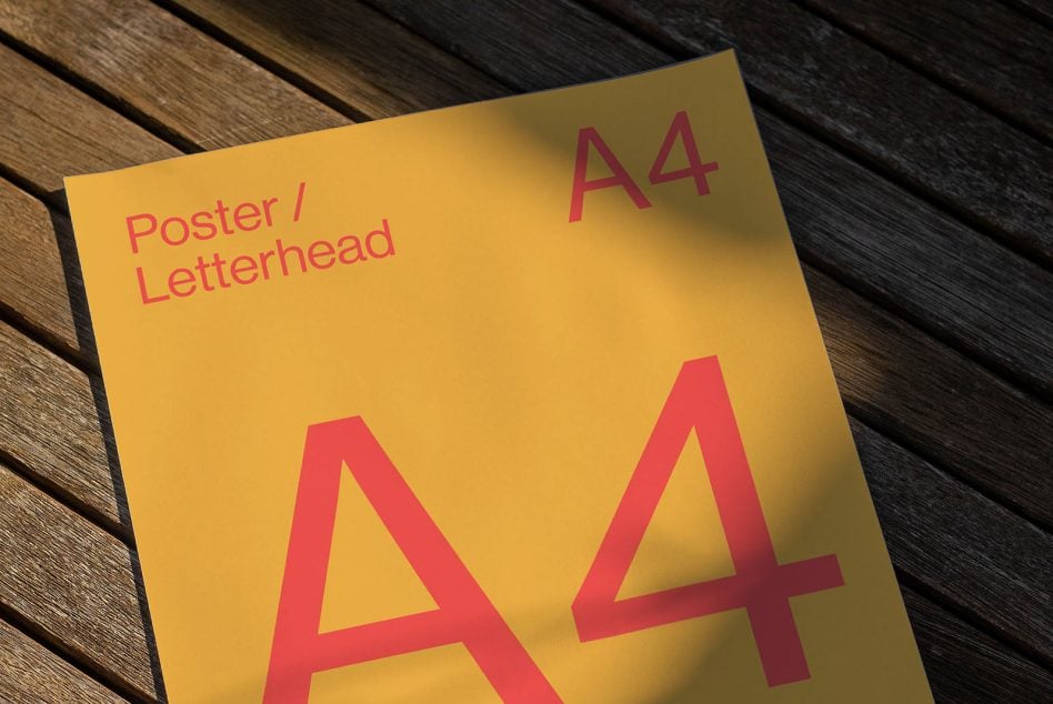 Yellow poster mockup angled on wood showing red A4 size lettering