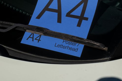 Close-up of A4 print mockup for poster or letterhead design showcasing under wiper blade of a car, with clear blue label and textures.