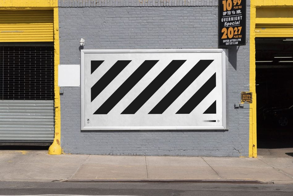 Small street-level signage showing diagonal stripe pattern on gray storefront with yellow trim