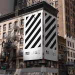 Urban billboard mockup on a building corner with black and white diagonal stripes, suited for designers to display advertising graphics.