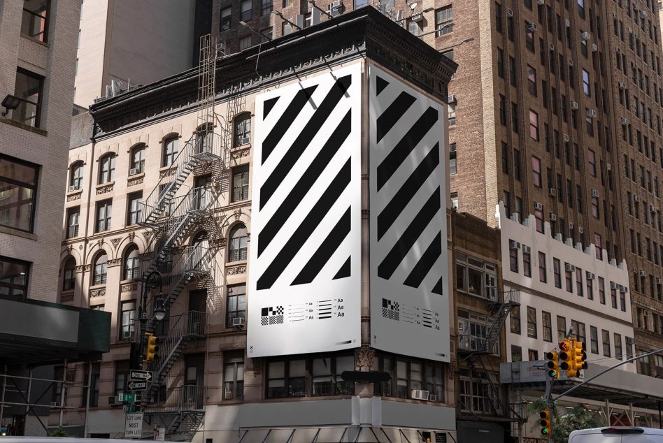 Urban billboard mockup on a building corner with black and white diagonal stripes, suited for designers to display advertising graphics.