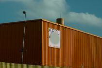 Industrial warehouse billboard mockup against blue sky with corrugated metal siding