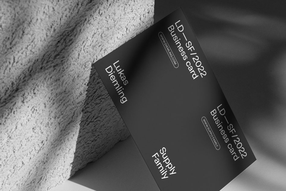 Two black business cards arranged on rough gray concrete with shadow detail