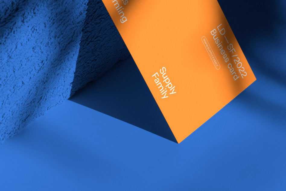 Bright orange business card laying on vibrant blue concrete texture background
