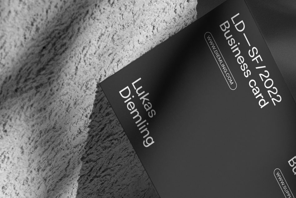 Black business cards stacked on textured concrete surface with white typography