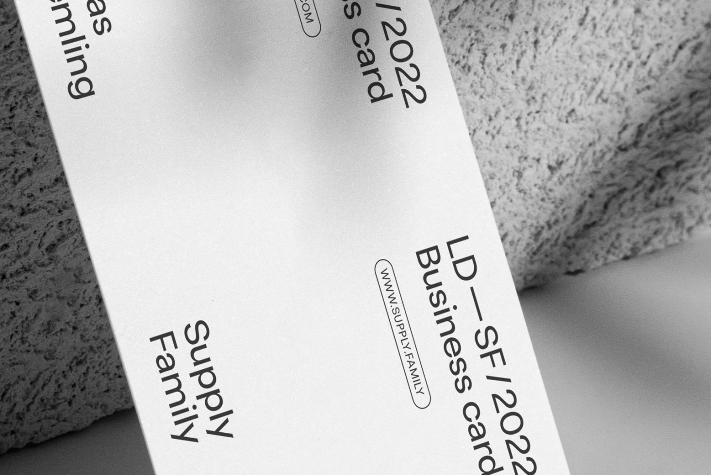 Stylish monochrome business card mockup on textured surface, modern design, angled view, perfect for designers to showcase branding.