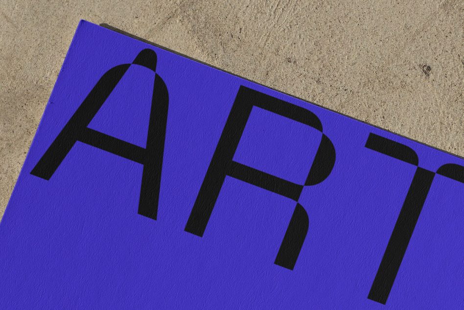 Bold black letters spelling ART on a vibrant purple background mockup, partially lying on a textured concrete surface.