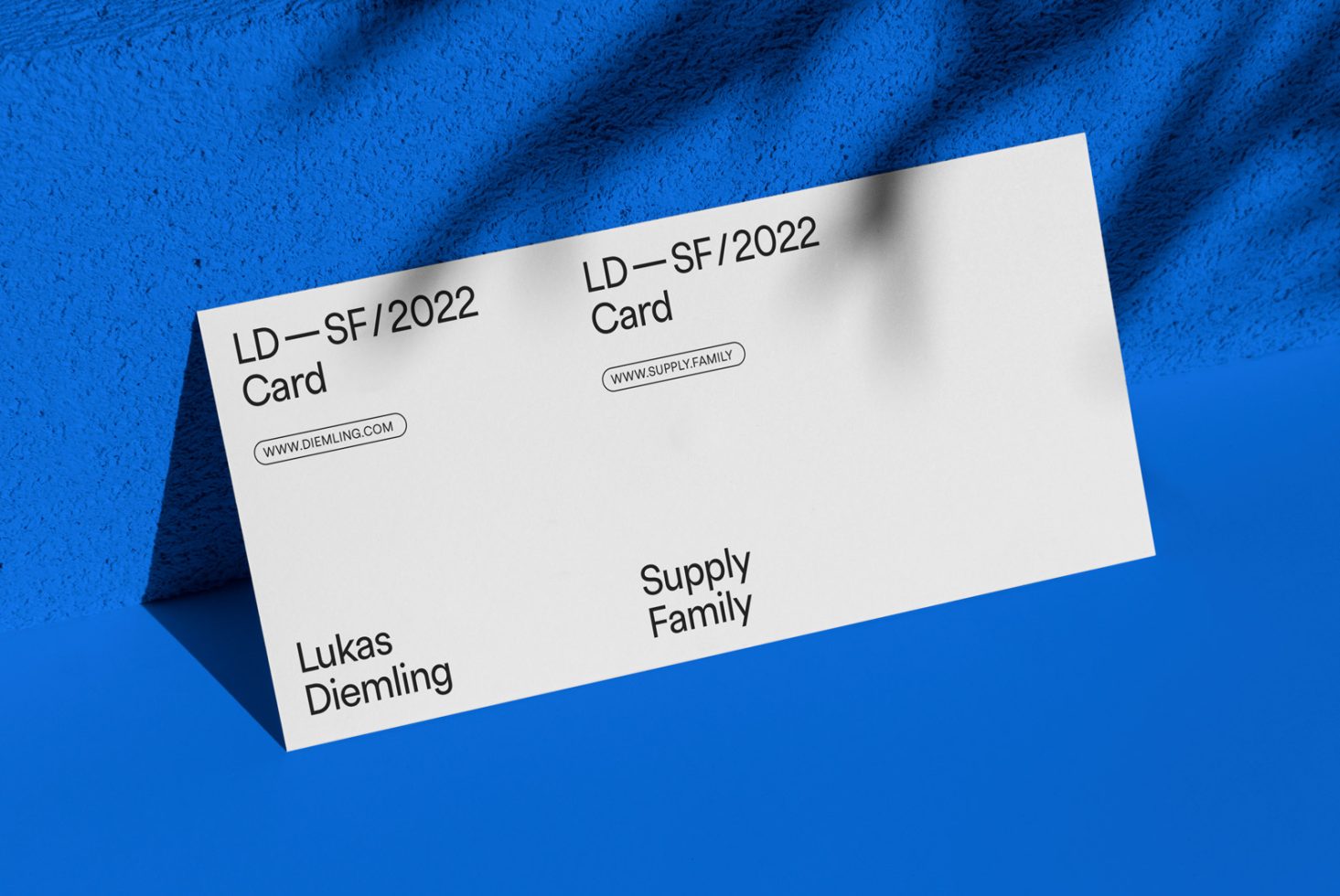 Business card mockup template with modern typography on a white card and blue textured background. Ideal for presenting branding designs for designers.