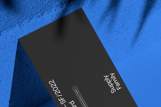 Elegant black business card mockup on blue fabric texture, showcasing clean design for presentation, digital asset for designers.