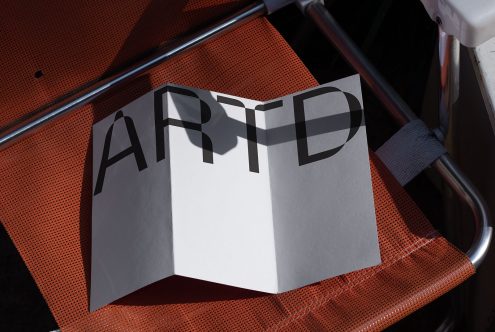 Folded paper brochure mockup with typographic design resting on orange seat for graphic display, modern presentation tool, design asset.