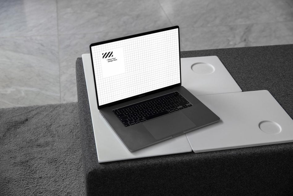 Laptop on desk with notebooks showing light grid pattern screen, clean modern workspace