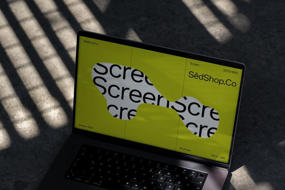 Laptop at angle on concrete with bright yellow screen displaying overlapping text mockup