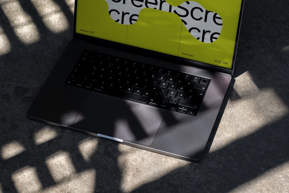 Overhead view of laptop with lime green display showing layered MockupScre typography