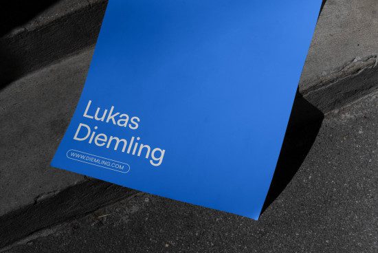 Blue business card mockup on a concrete step with minimalist design, showcasing clean font style, suitable for designers and branding.