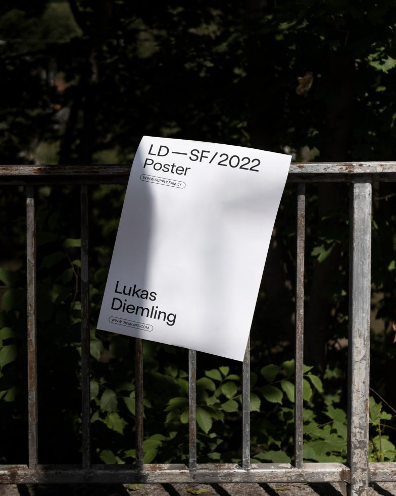 Clean poster mockup displayed on a metal fence outdoors, ideal for presenting fonts and graphic design in a natural setting.