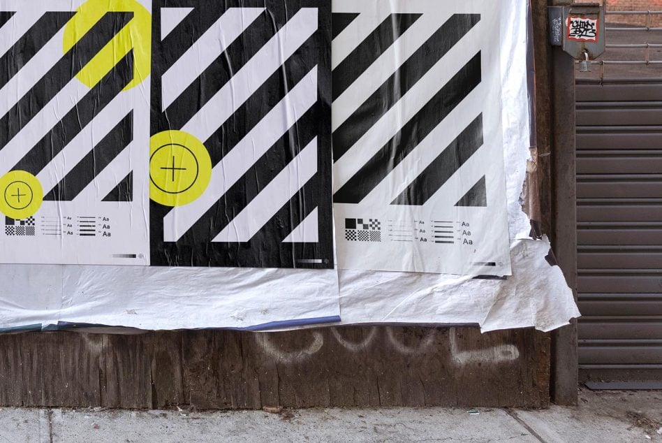 Two large diagonal stripe posters on storefront window, yellow highlighted sections, weathered wood base