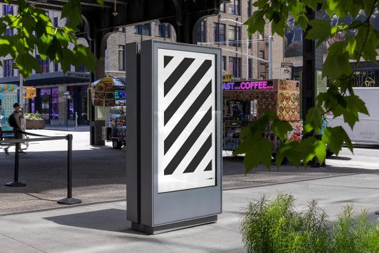 Urban street kiosk mockup with diagonal stripe design, set against a lively city backdrop with pedestrians and storefronts, perfect for advertising presentations.