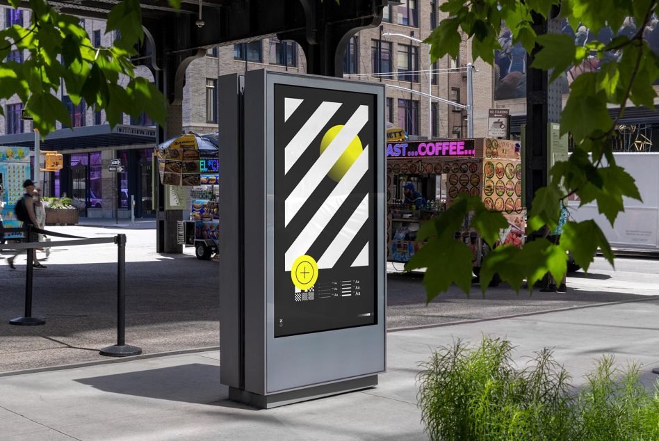 Street kiosk display with diagonal stripe design, black background, yellow accent elements, city scene behind