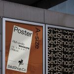 Poster mockup showcased on urban store wall, featuring design template in a modern setting for branding preview.