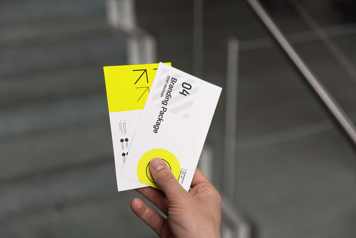 Hand holding vibrant yellow and white business card design mockup near staircase, showcasing modern branding package.