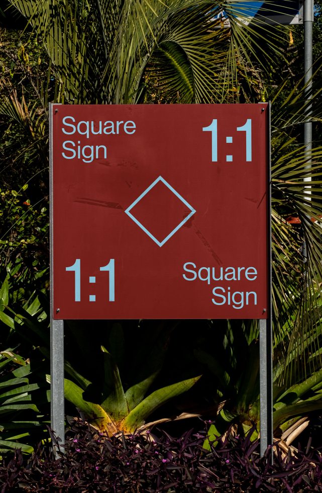 Red square sign mockup with tropical foliage background, clear skies, for outdoor advertising and graphic design presentations.