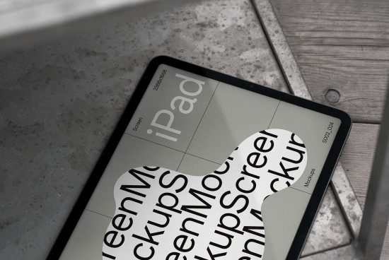 iPad screen mockup on concrete surface with wood accents, showcasing digital design with typography emphasis for creative presentations.