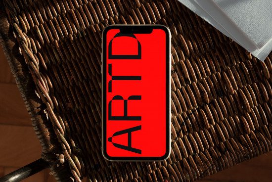 Smartphone screen mockup on wicker texture displaying custom red graphic design, showcasing bold font for digital asset marketplace.