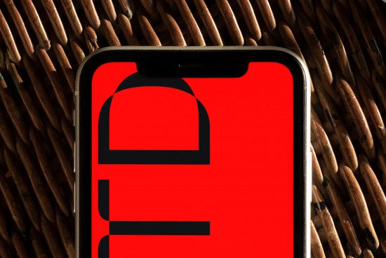 Smartphone on wicker background with red screen for app design mockup, digital asset for graphic designers and template.