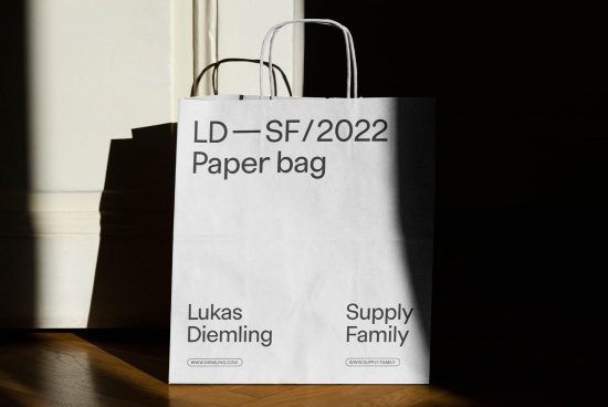 White paper shopping bag with minimalistic typography design in sunlight, creating contrast shadow, ideal for mockup and branding presentations.