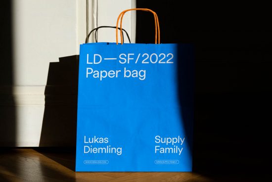 Blue paper bag mockup with typography design in sunlight and shadow, ideal for branding presentations and packaging designs.